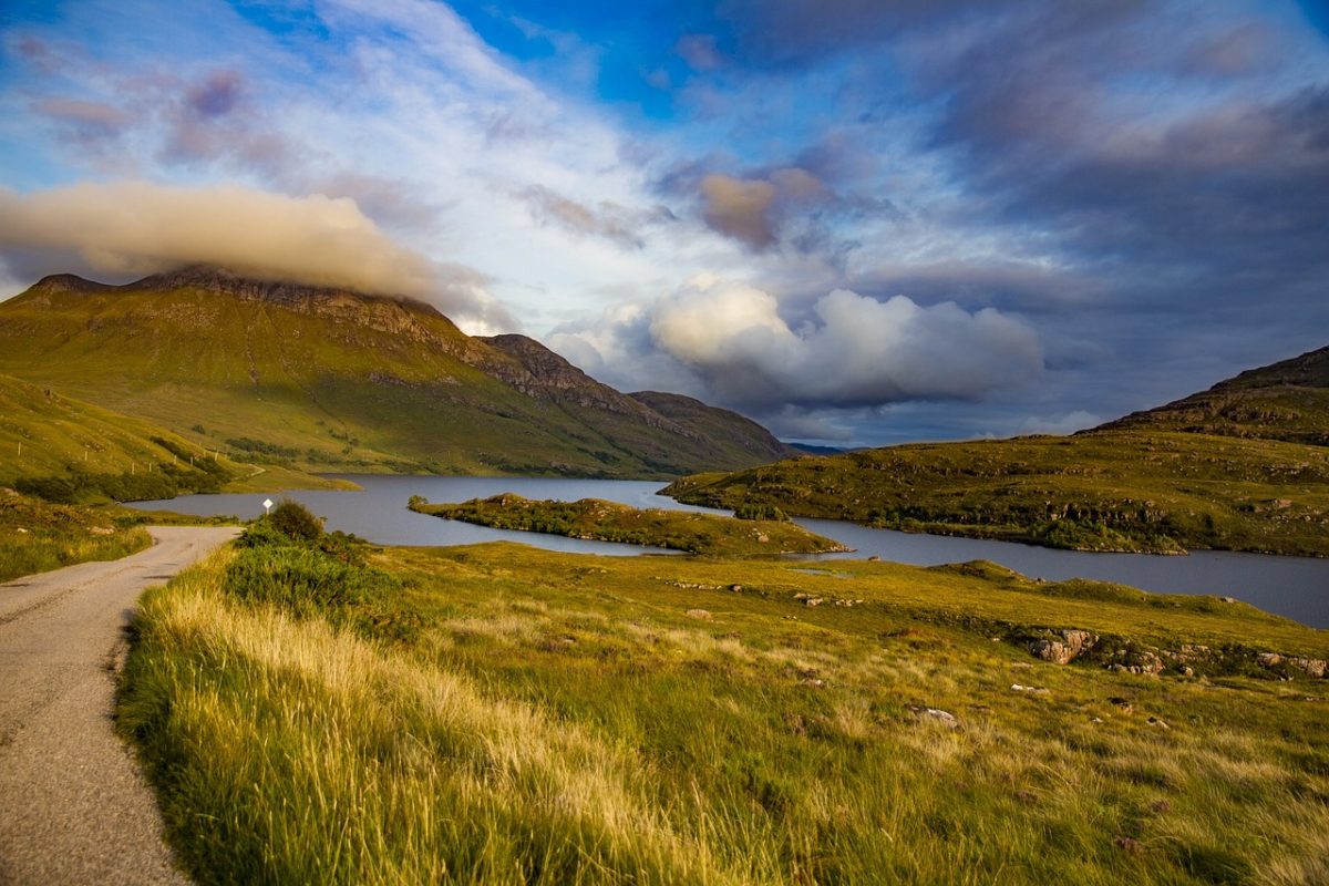 Bild einer atemberaubenden schottischen Landschaft, geprägt von sanften grünen Hügeln, wilden Hochmooren und einem dramatischen Himmel, der die unberührte Schönheit Schottlands einfängt.